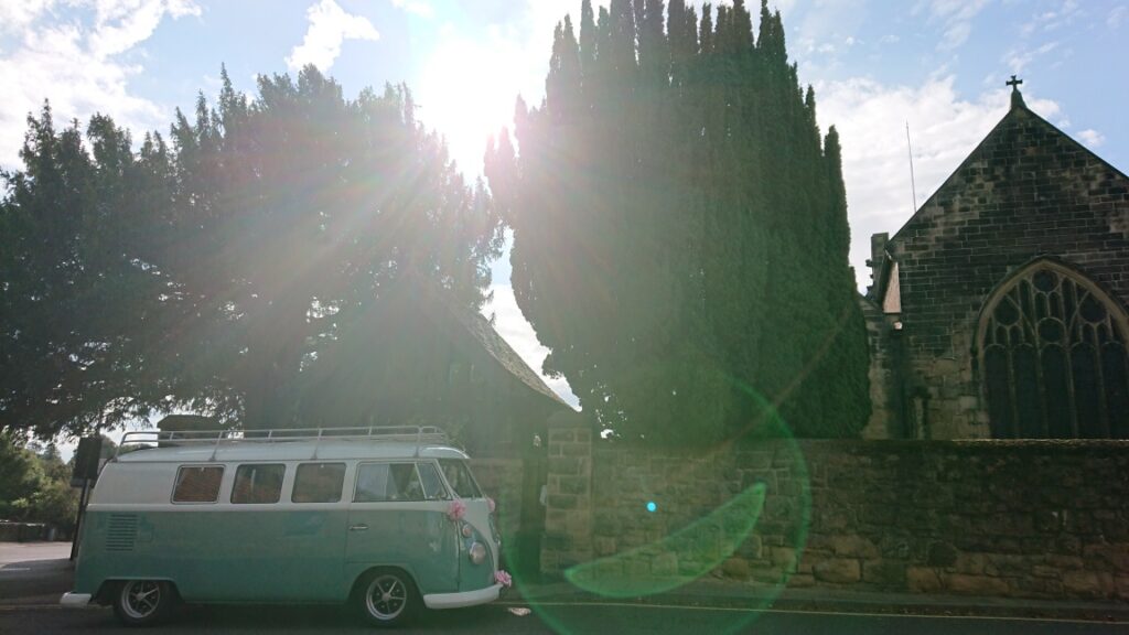 vw campervan parked outside a church in the sun